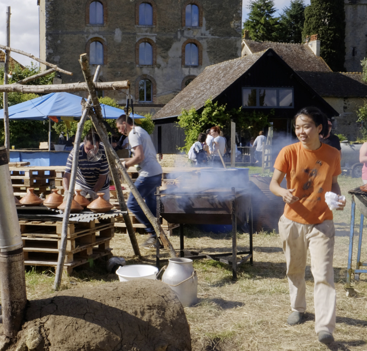 une femme avec un teeshirt orange dans un jardin pres d'un barbecue